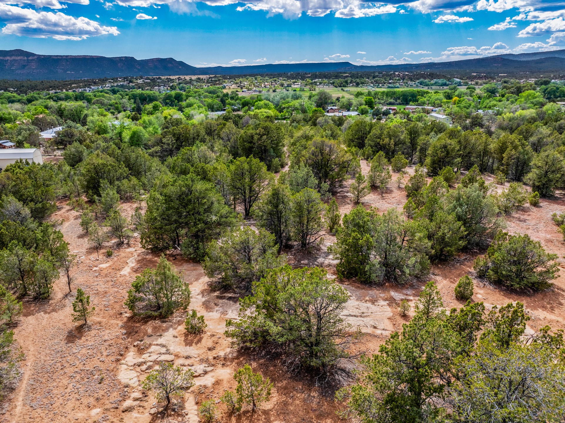 Aerial view of wooded, rocky land with homes and mountains in the distance.