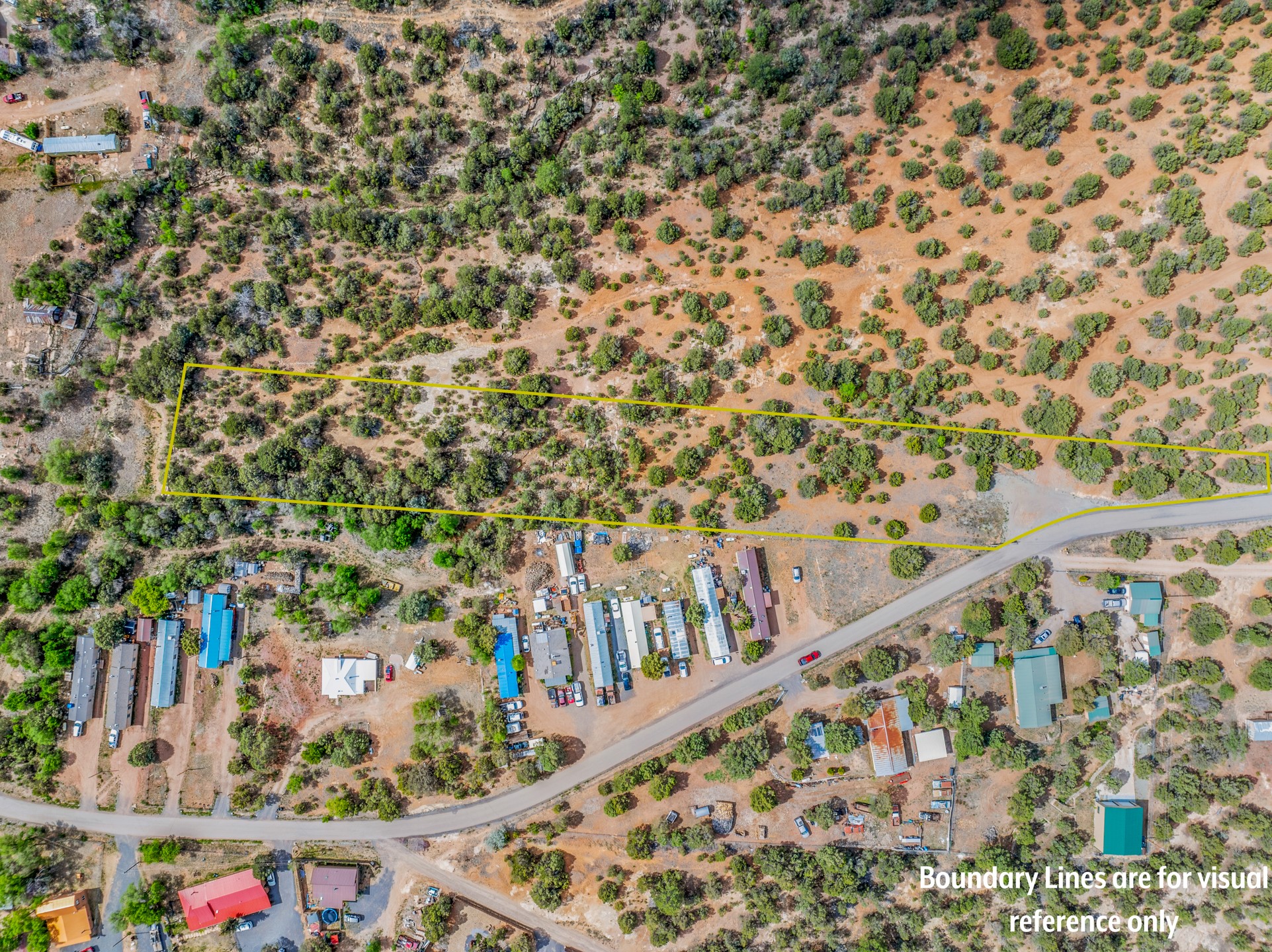 Aerial view of brush-covered land outlined in yellow beside a paved road and nearby homes.