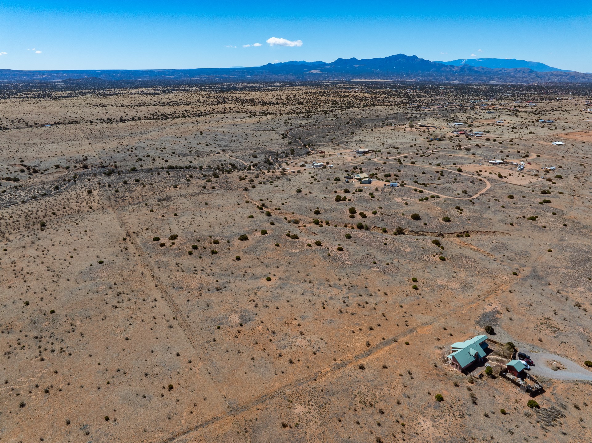 Aerial view of arid acreage with scattered homes and a distant mountain range.