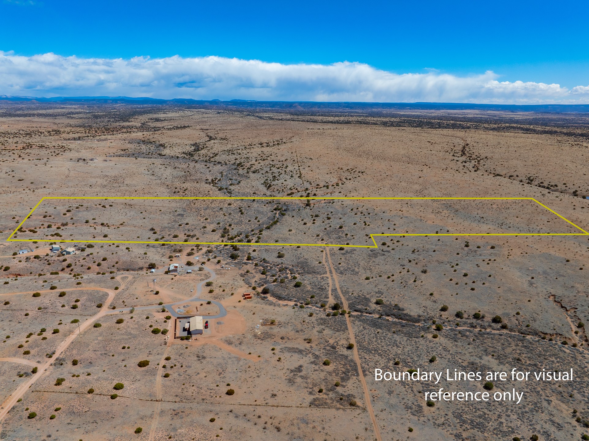 Aerial view of scrubland outlined in yellow, with dirt roads and a few nearby buildings.