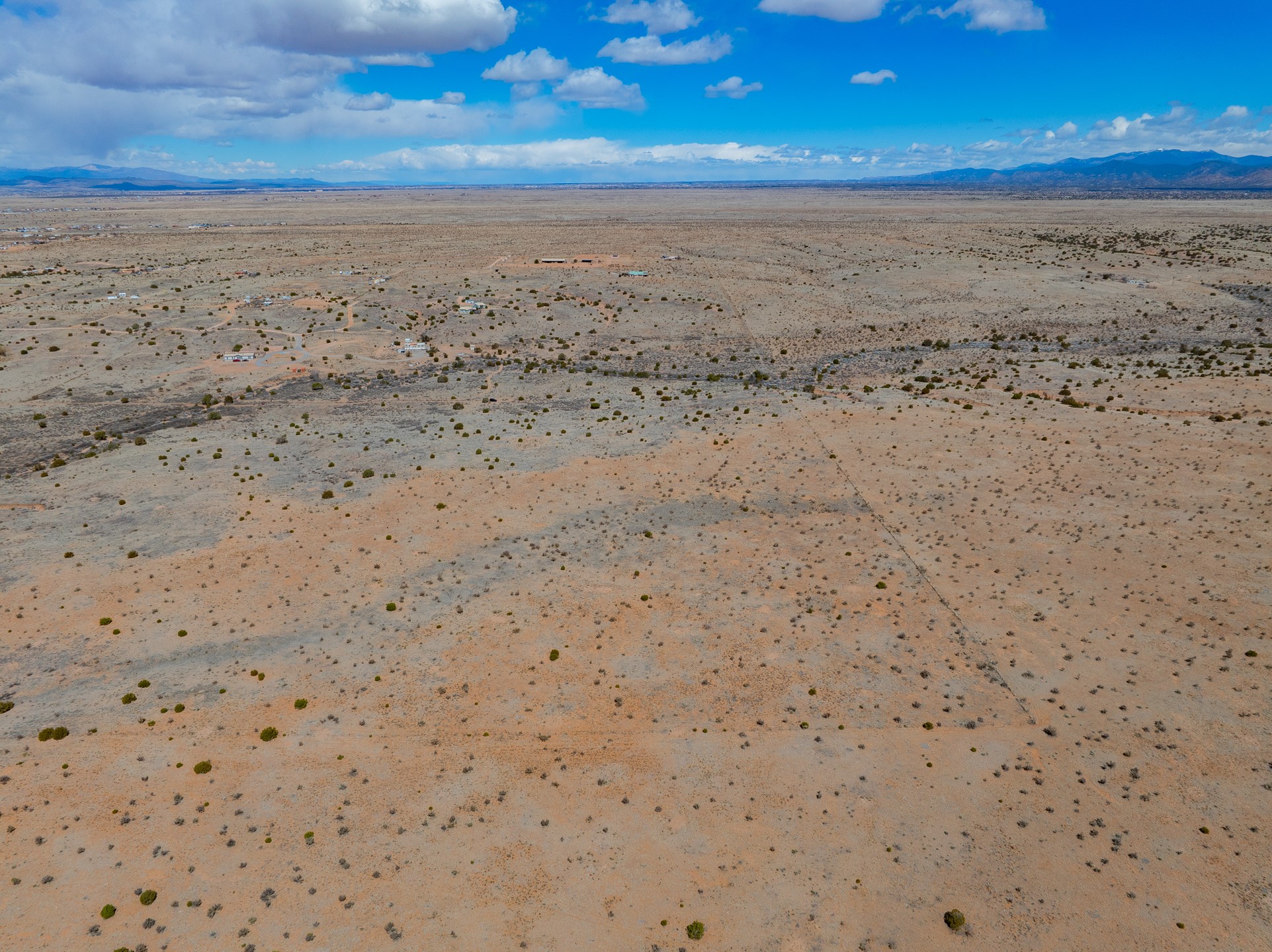 Aerial view of undeveloped desert acreage with sparse shrubs and distant mountain ranges.