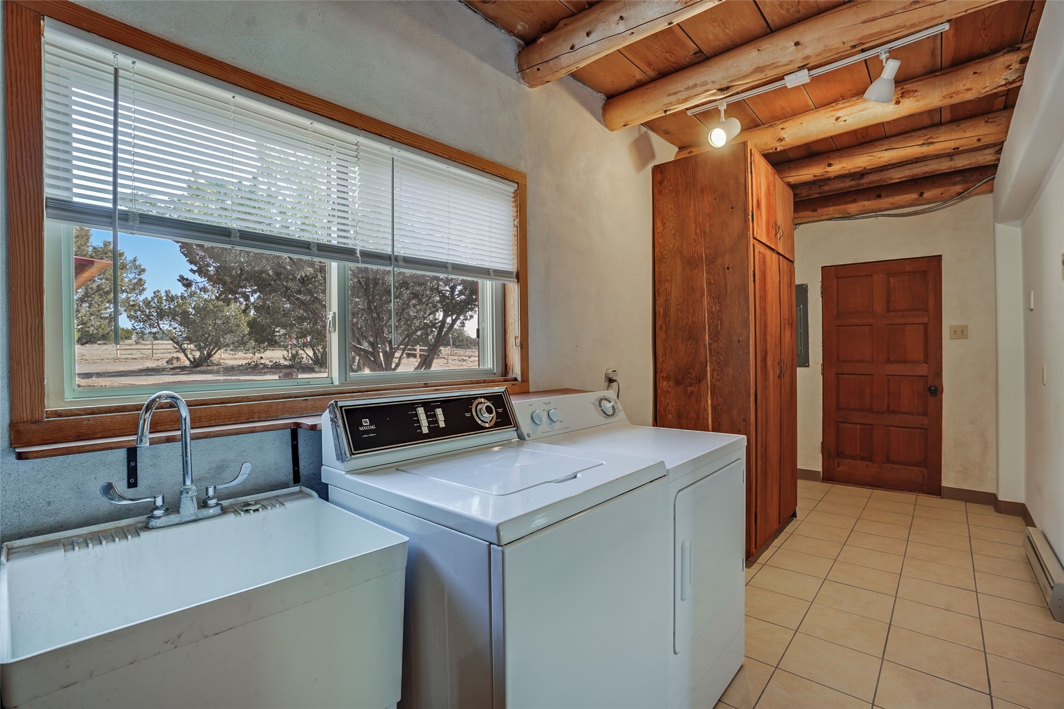 Laundry room with washer, dryer, and utility sink beneath a large window.