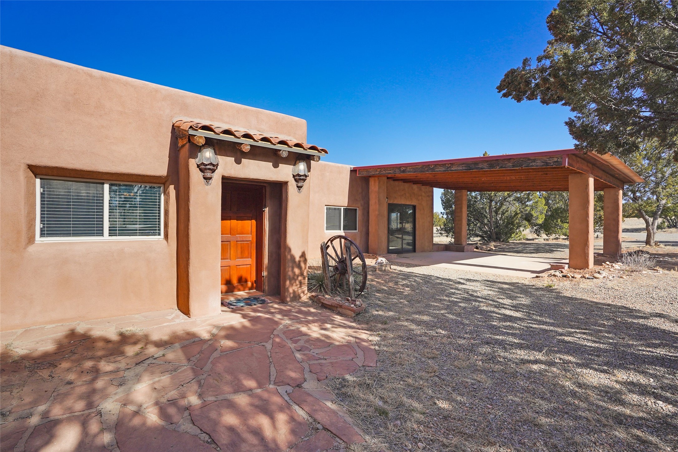 Southwestern stucco home with a red front door and broad covered patio.