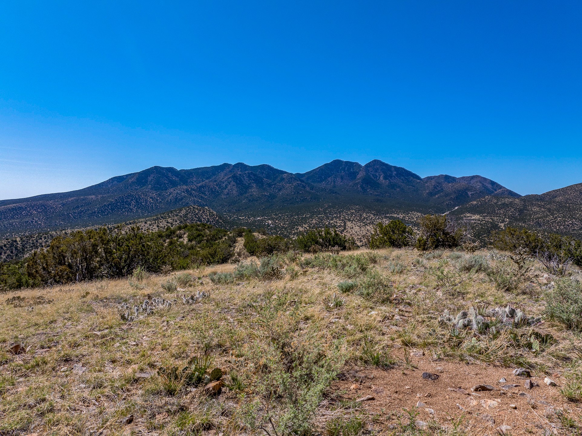 Vacant high-desert land with rocky scrub and a broad view of rugged mountains.