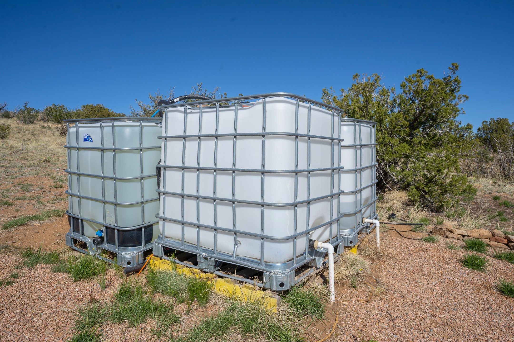 Caged water storage tanks on a dry, scrub-covered property.