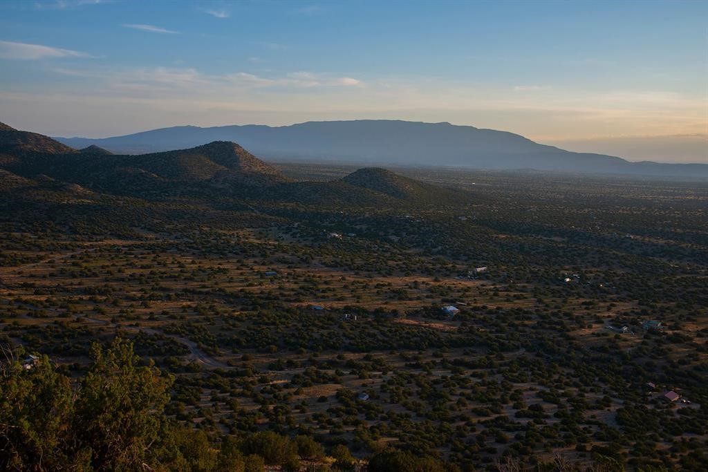 Desert scrubland and scattered homes stretch toward foothills and a distant mountain range in evening light.