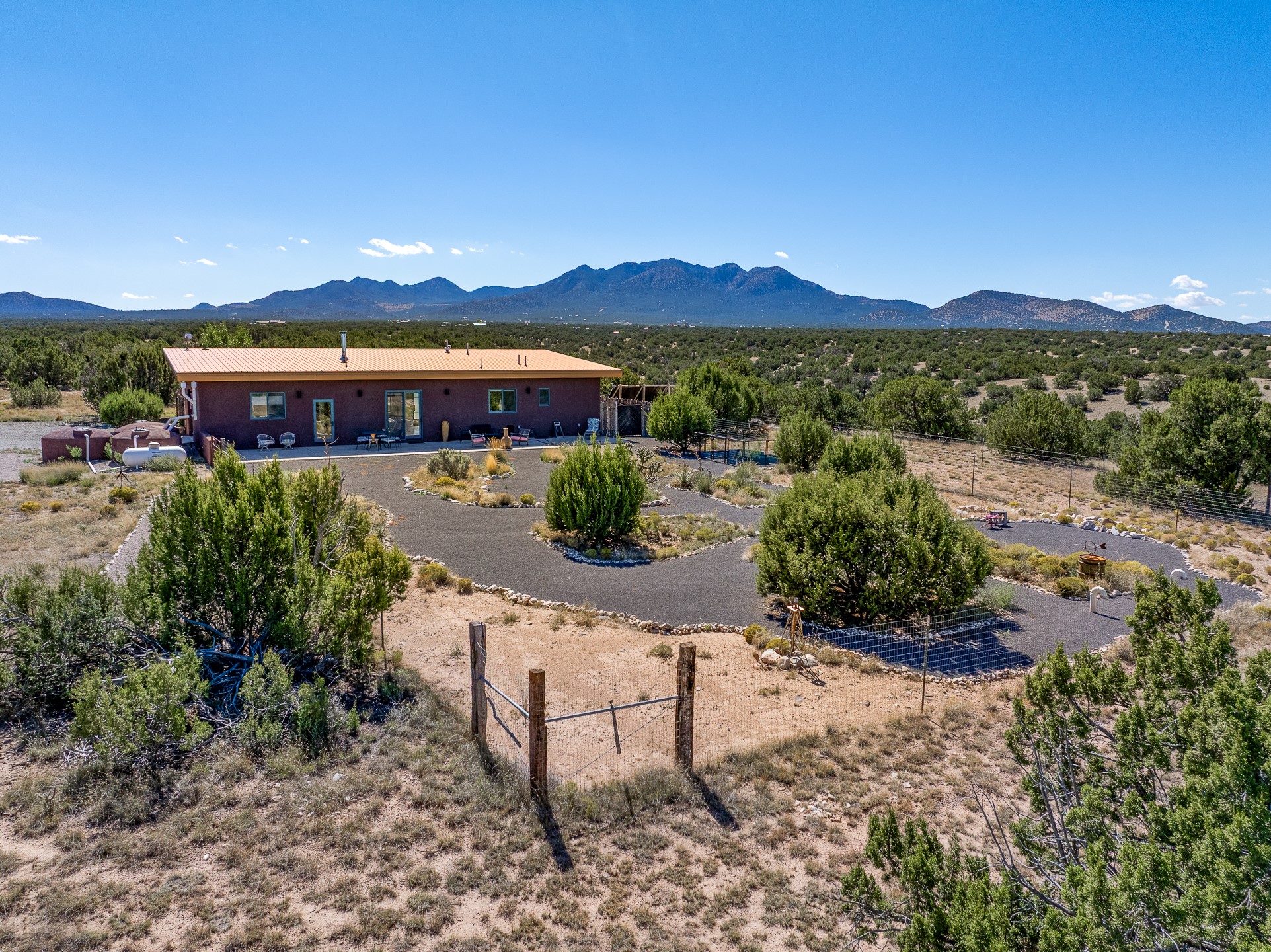 Single-story desert home with a gravel drive, fenced yard, and mountain backdrop.
