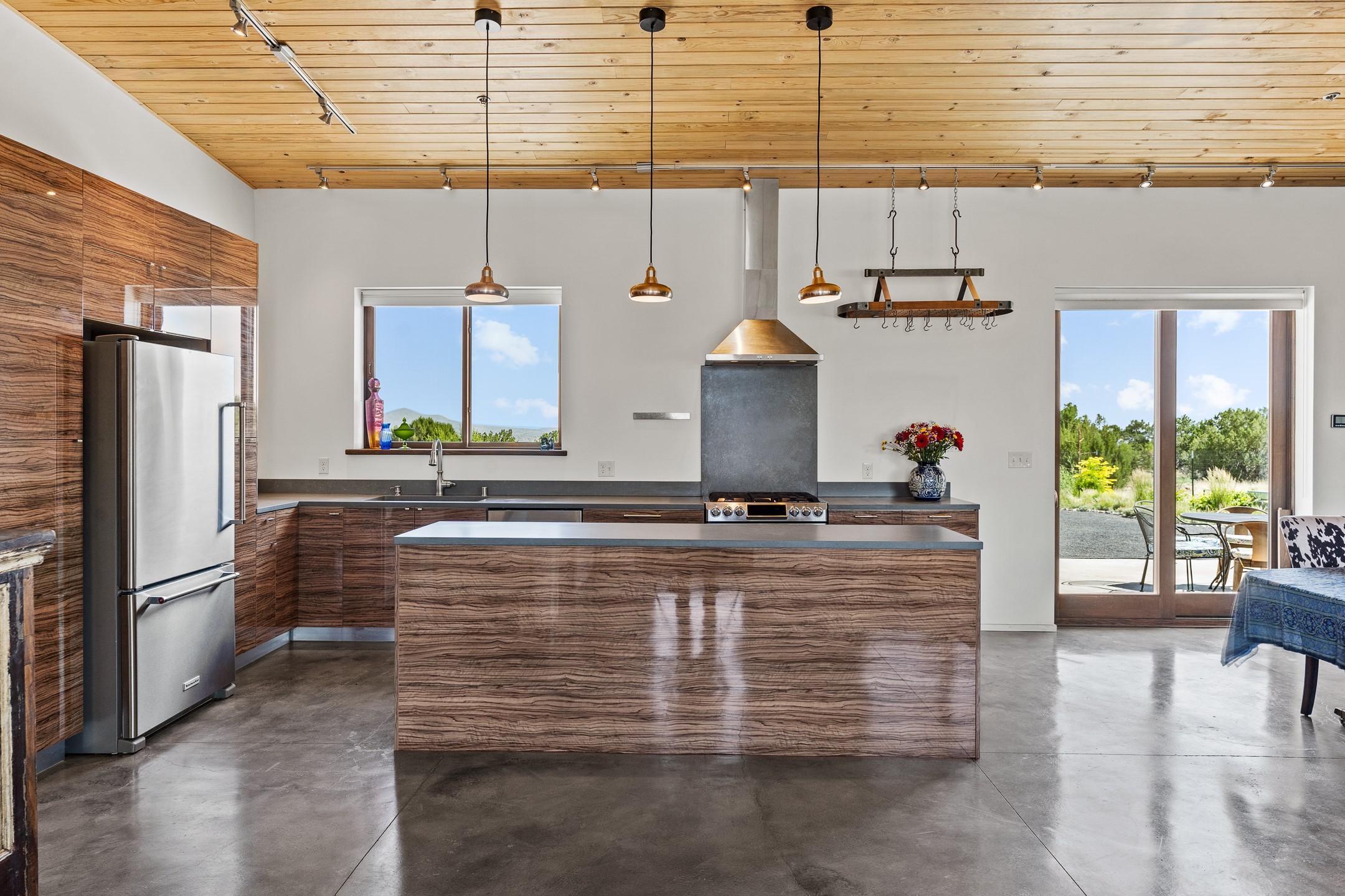 Modern kitchen with a broad wood-grain island, stainless refrigerator, and sliding doors to the patio.