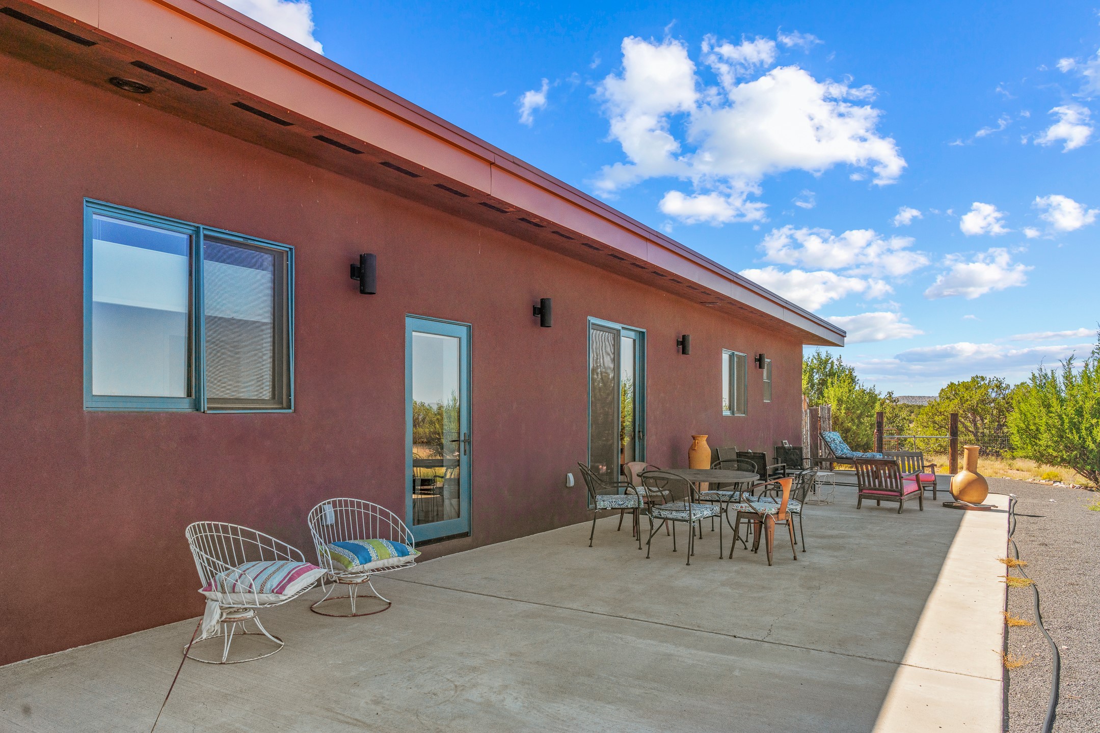Concrete patio beside a reddish-brown home, furnished with dining and lounge seating.