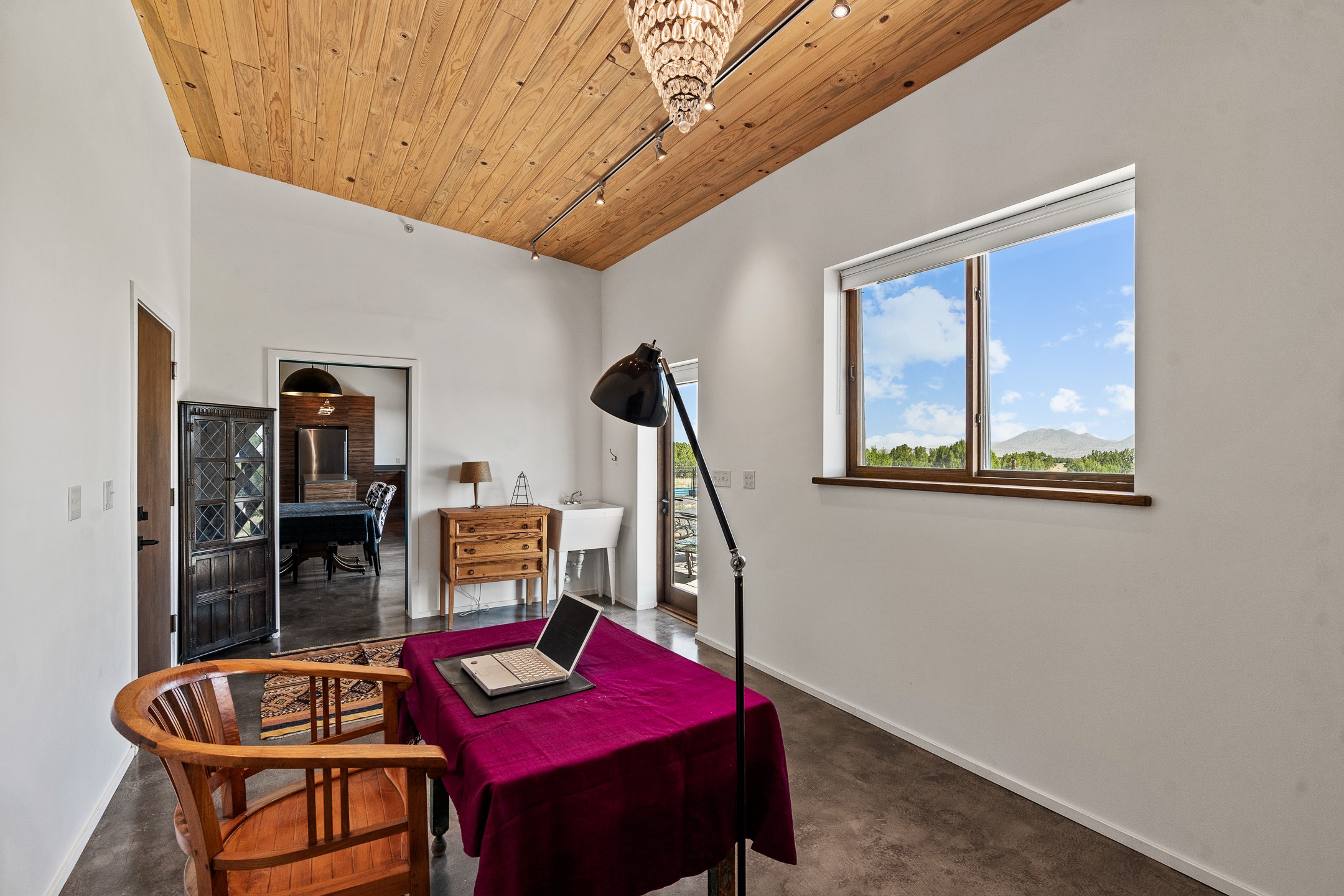 Furnished home office with a wood ceiling and mountain views through a large window.