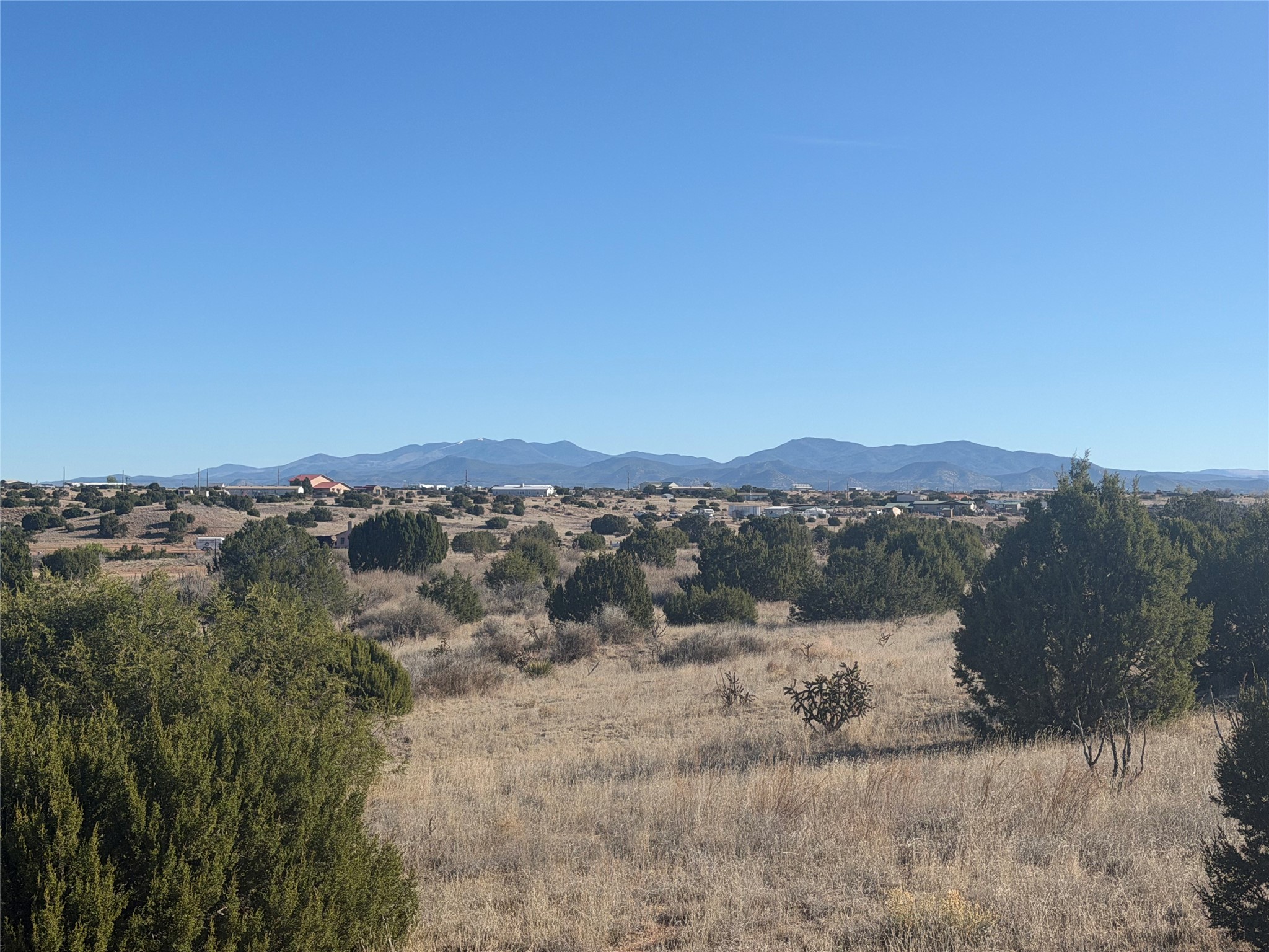 Open shrubland with distant mountain views and homes along the horizon.
