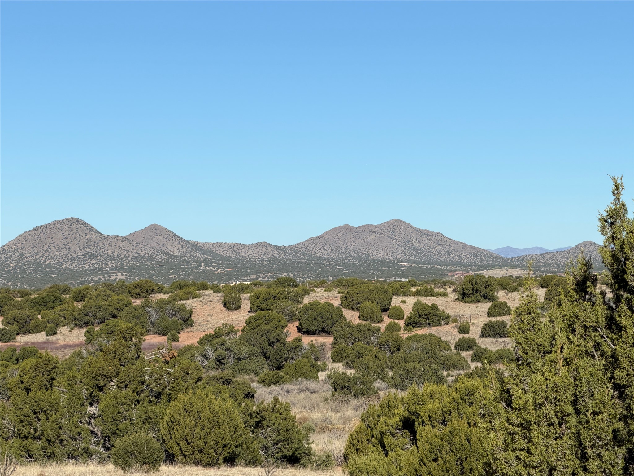 Undeveloped, shrub-covered land with a panoramic view of rocky mountains.