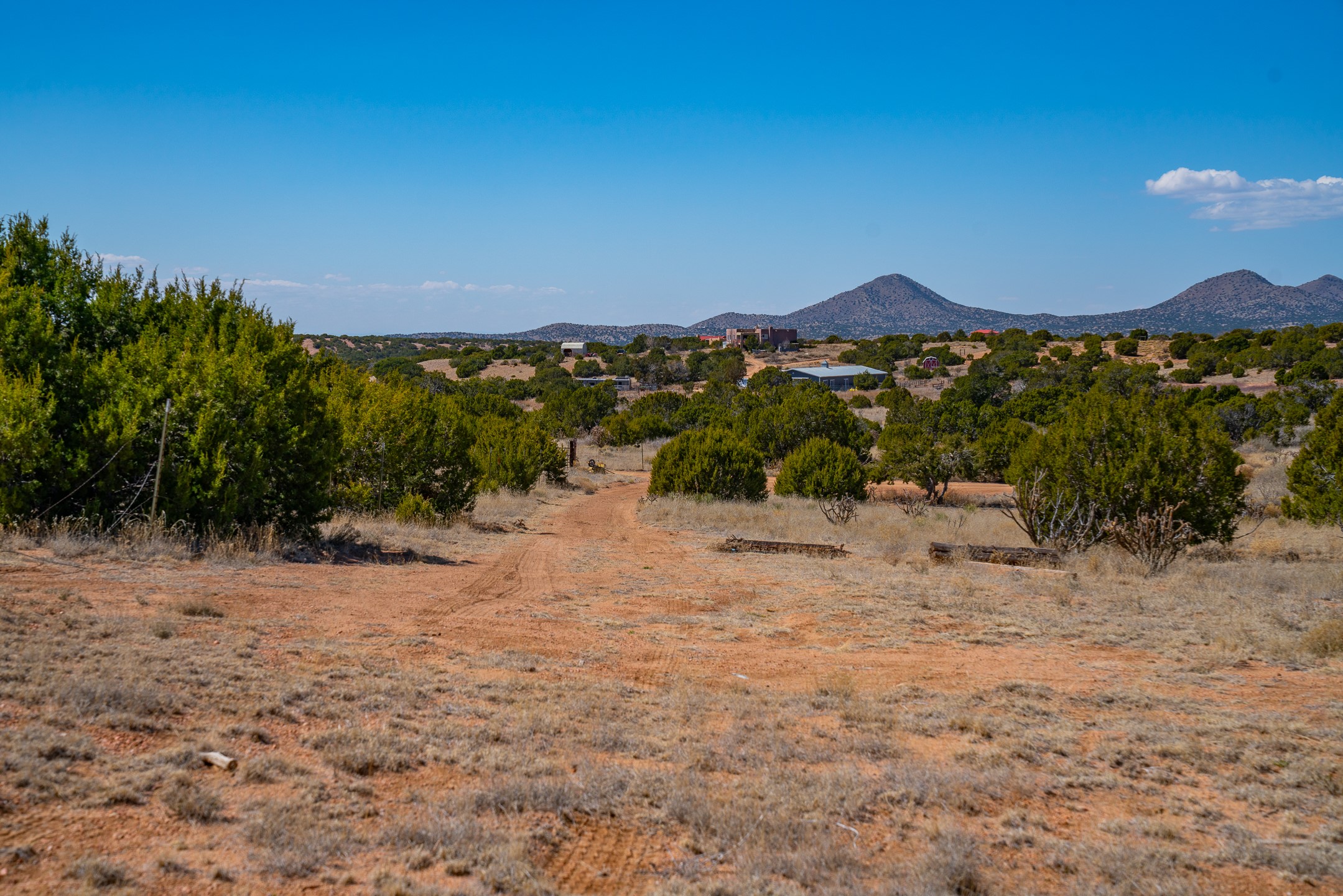 Vacant high-desert property with a dirt track, scattered shrubs, and distant mountains.