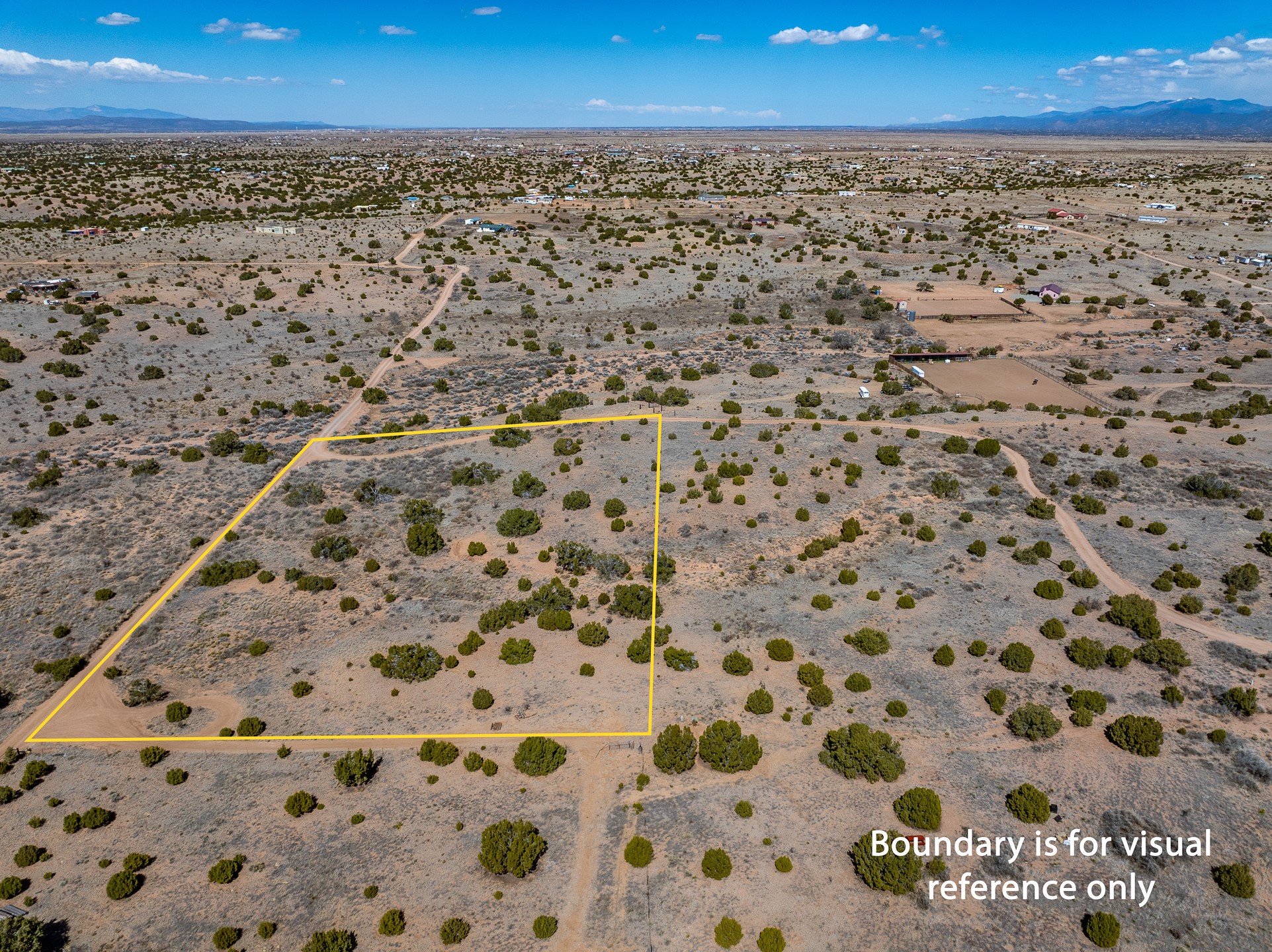 Aerial view of scrub-covered land parcel outlined in yellow, with distant mountains.
