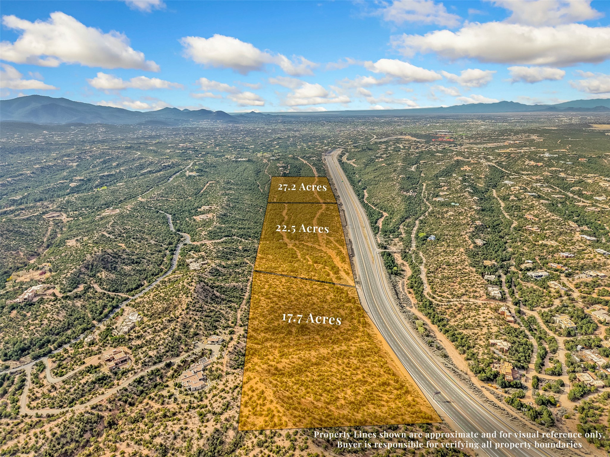 Aerial view of three outlined acreage parcels beside a highway, with scattered homes and distant mountains.