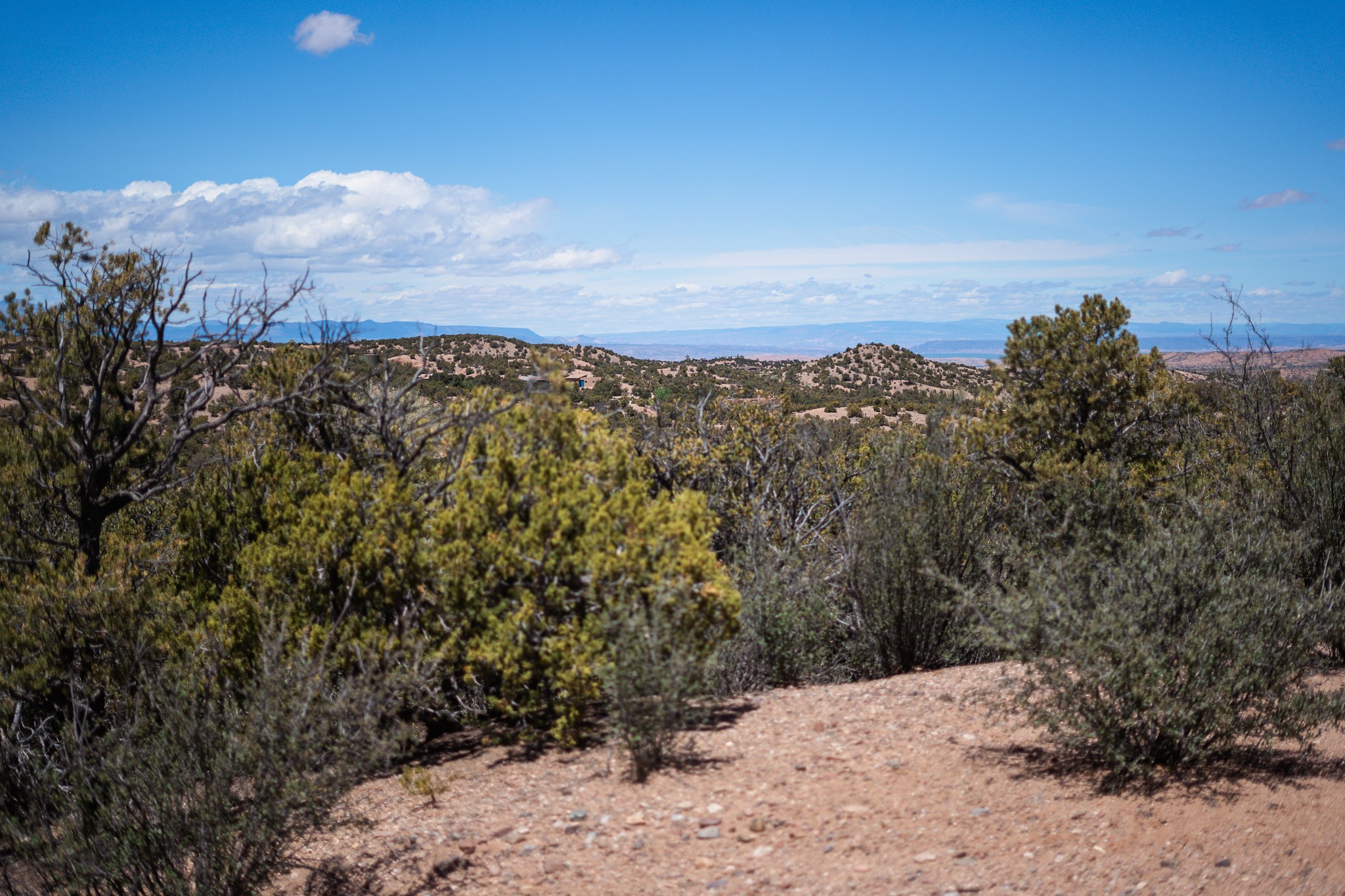 Undeveloped acreage with juniper and scrub-covered hills and distant mountain ridges.