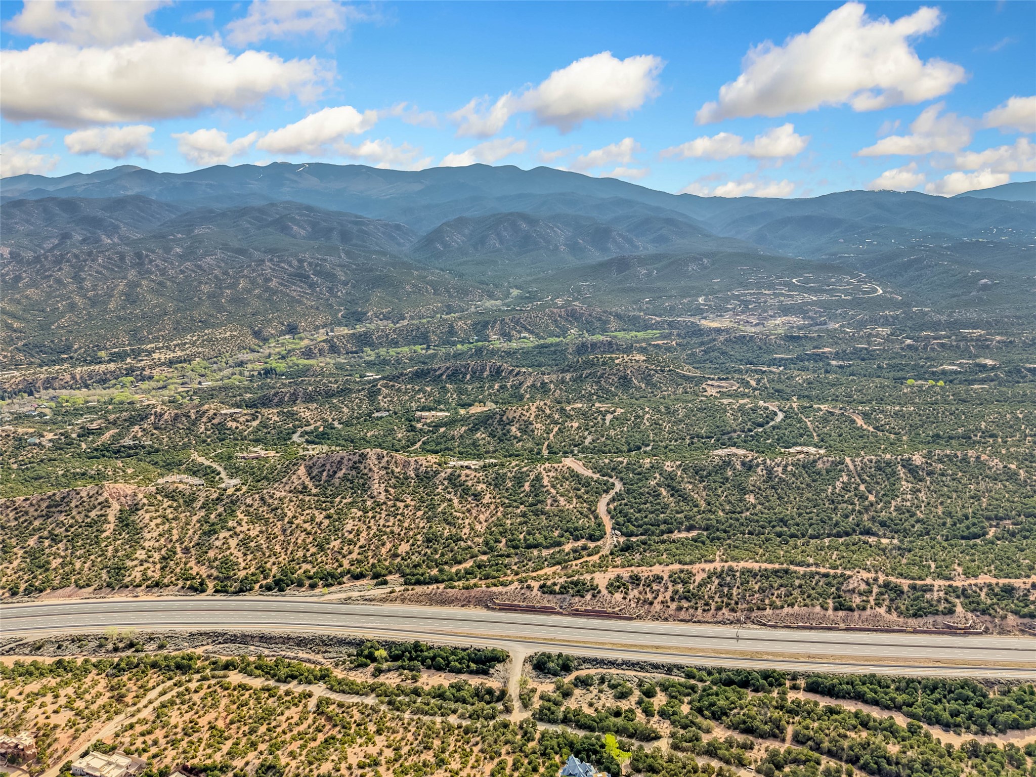 Aerial view of rugged acreage with a highway in the foreground and mountain ridges beyond.
