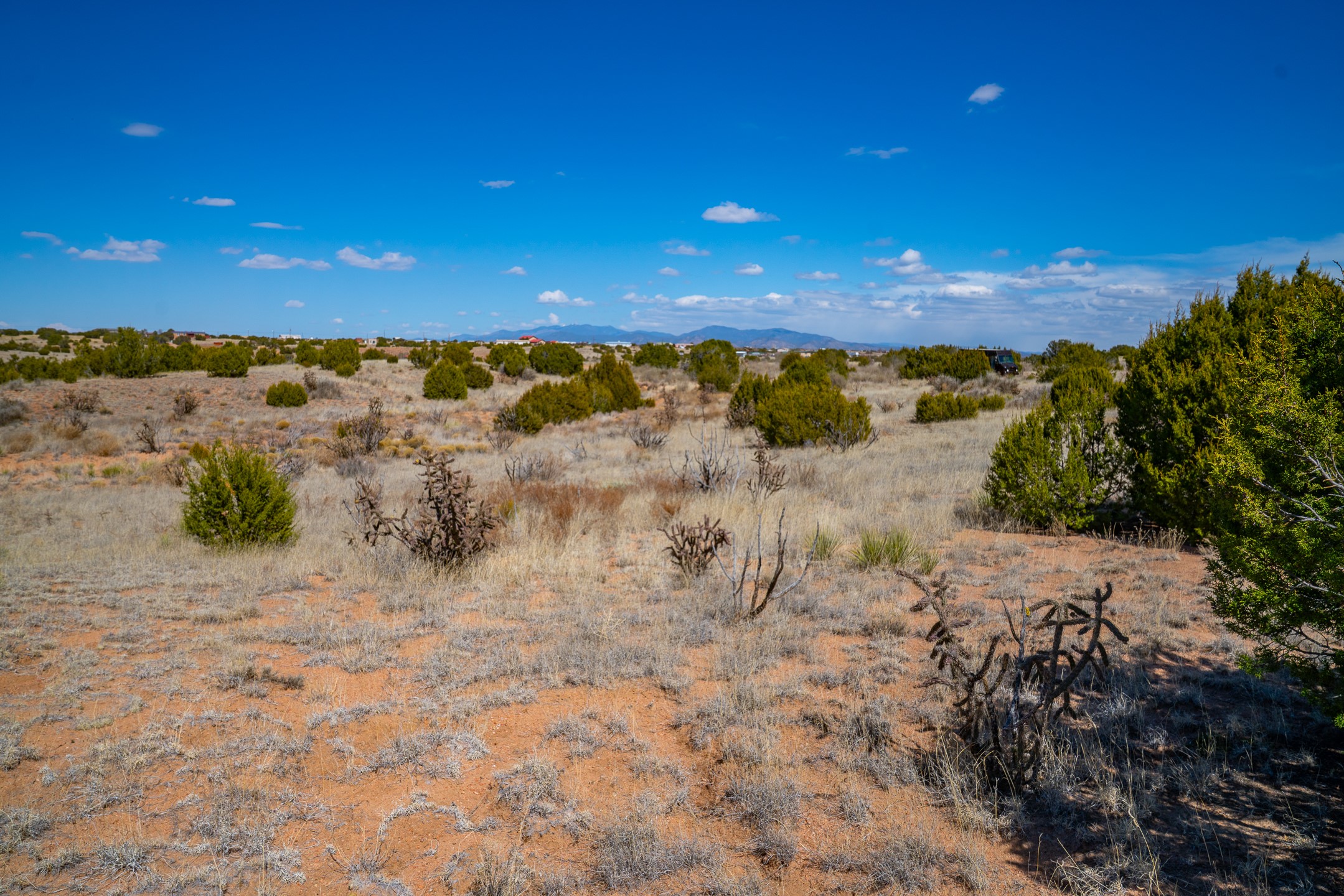 Vacant high-desert land with sparse shrubs and distant mountain views.