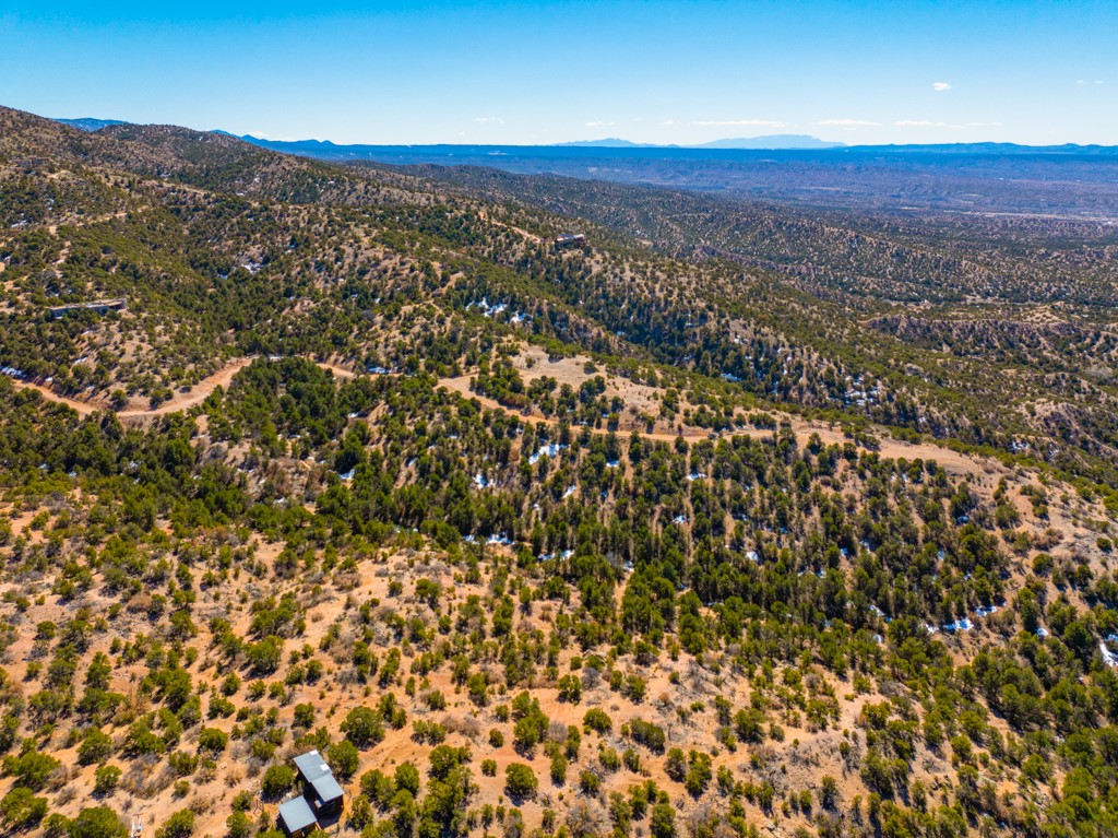 Aerial view of wooded mountain lots with winding dirt roads and distant ridges.