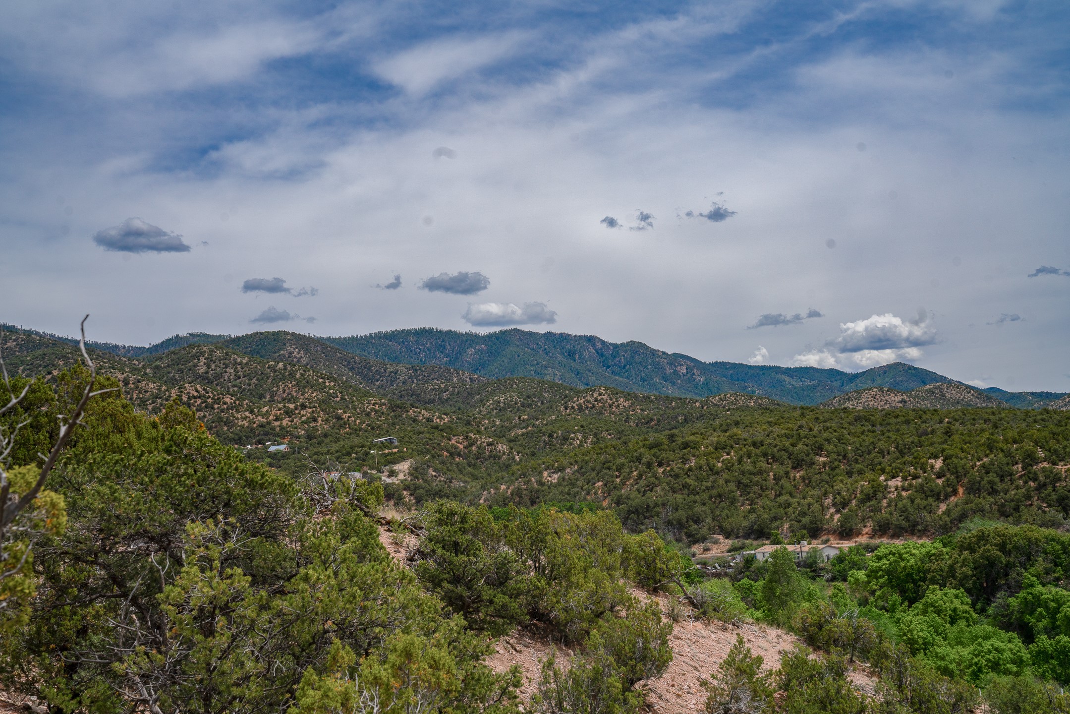 Wooded hills and distant mountain ridges beneath a partly cloudy sky.