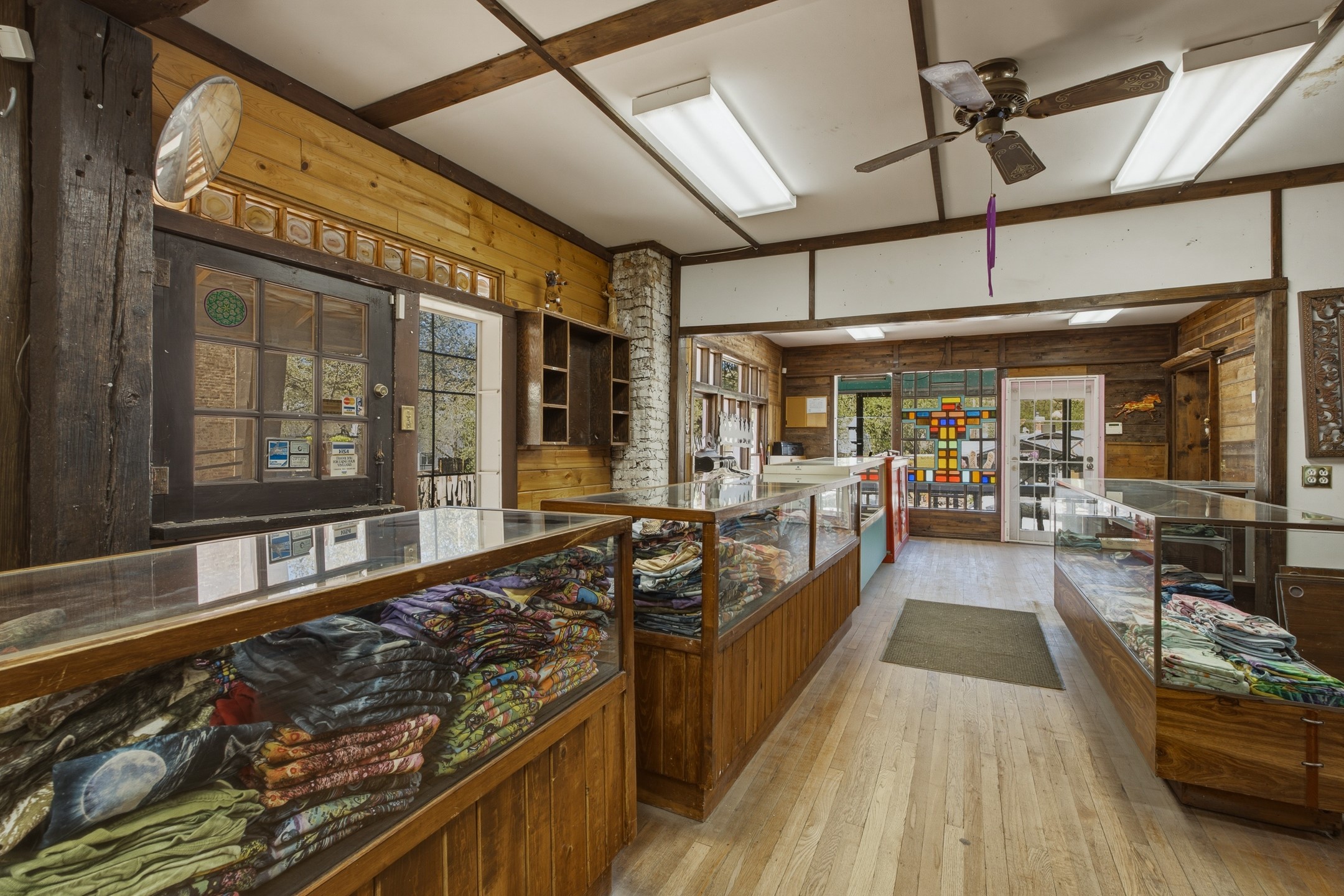 Rustic textile shop interior with glass display cases of folded colorful fabrics and exposed wooden beams.