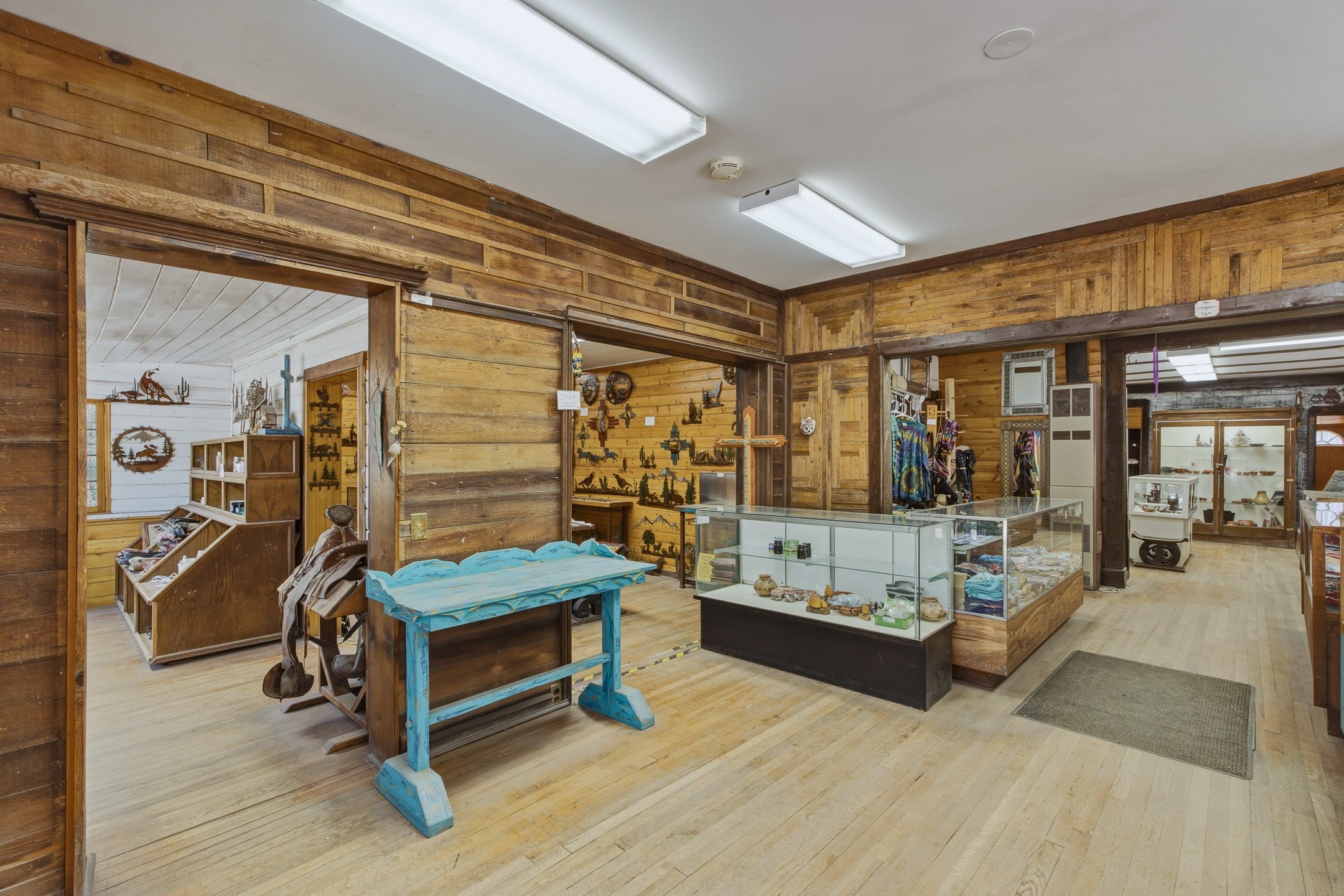 Rustic shop interior with glass display cases and a turquoise wooden table.