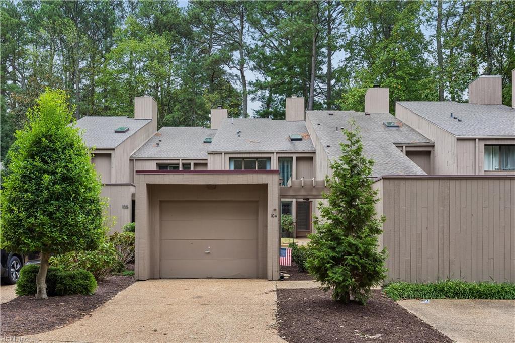 Townhouse exterior with a single garage, shared driveway, and mature trees.