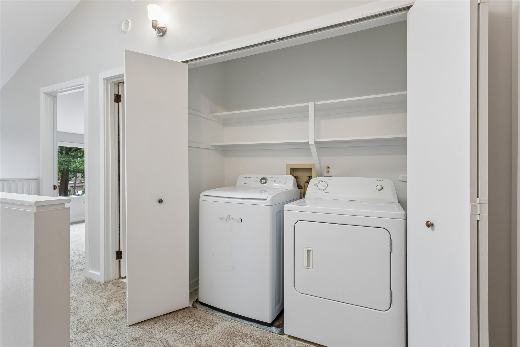 Laundry room with a washer and dryer beneath built-in open shelves.