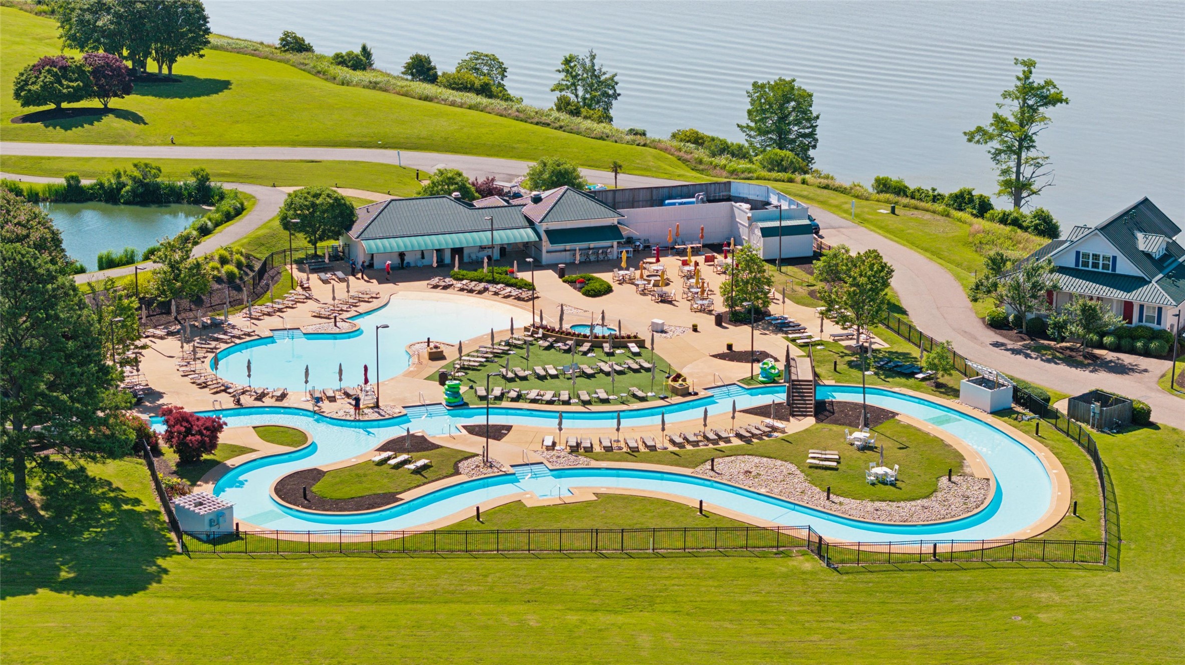 Aerial view of a community pool complex with a winding lazy river beside the water.