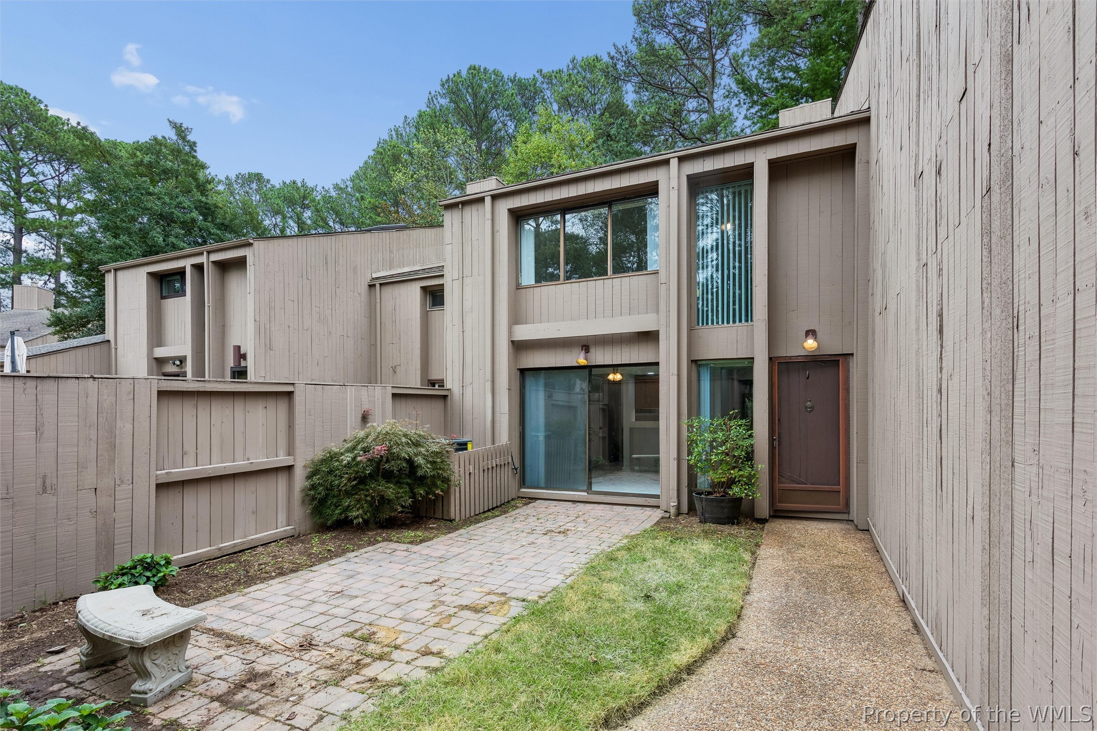 Townhouse courtyard with a paver patio, sliding glass door, and fenced garden.