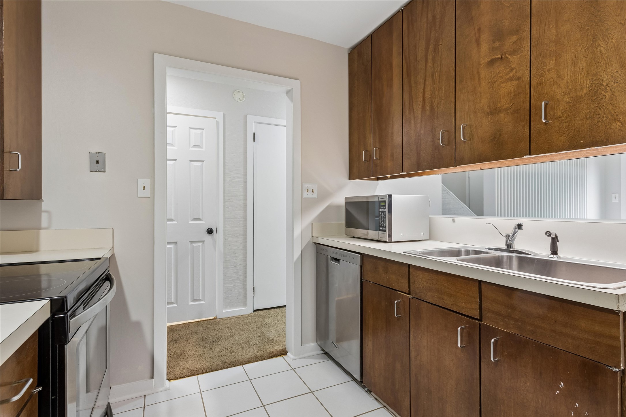 Kitchen with brown wood cabinets, a double-basin sink, microwave, and dishwasher.