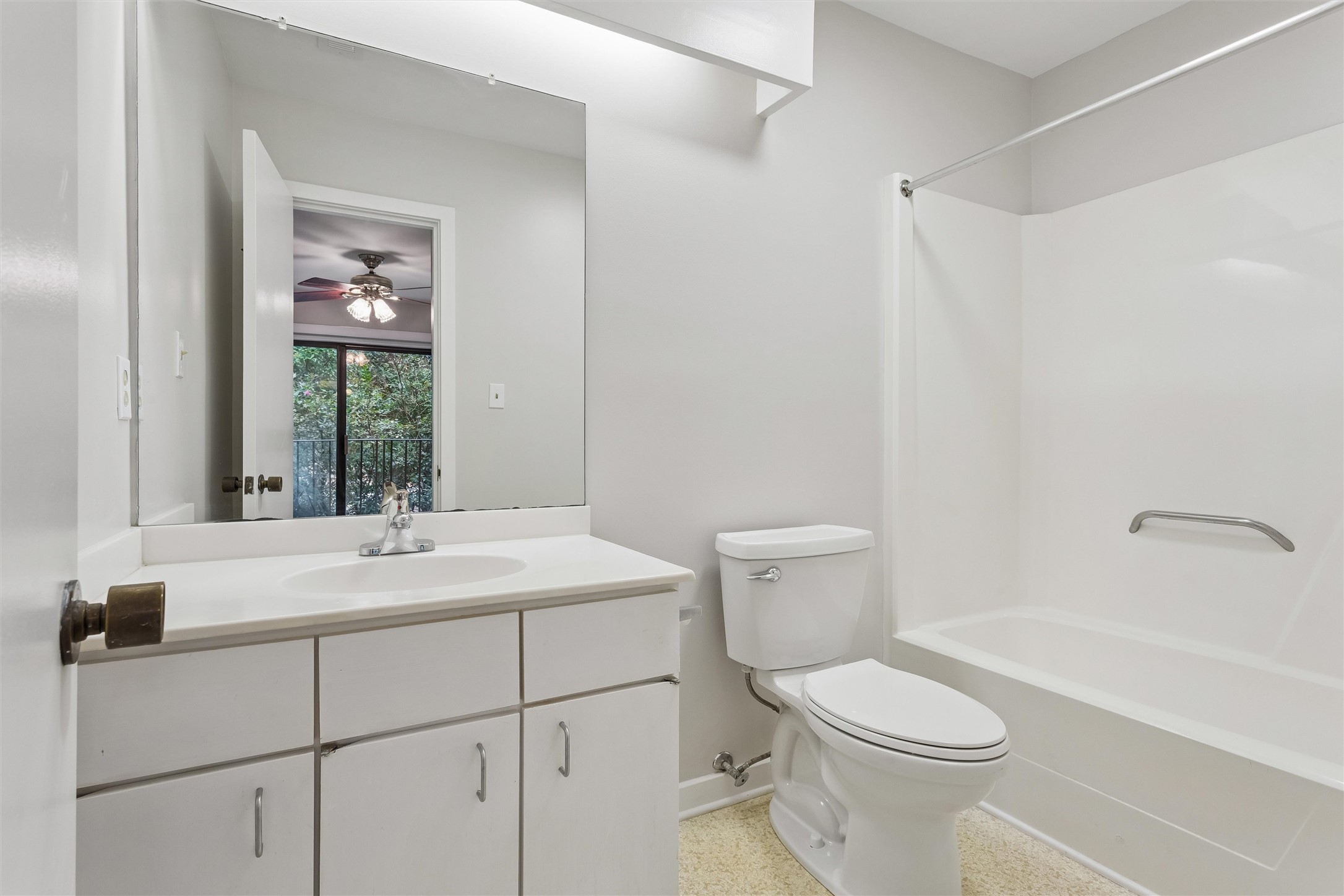 Bathroom with a white vanity, large mirror, toilet, and tub-shower.