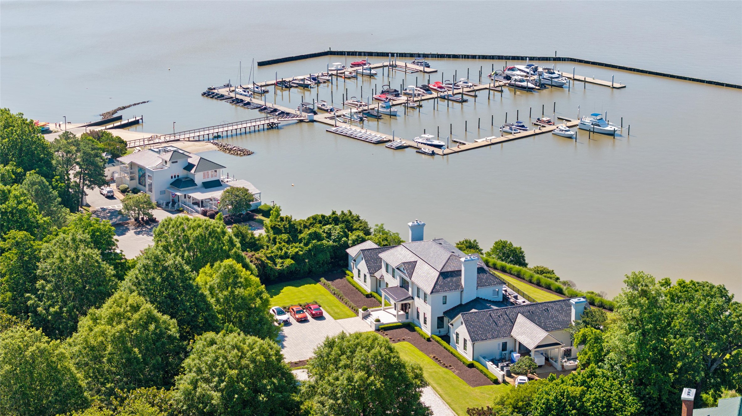 Waterfront home beside a marina with boats, seen from above.