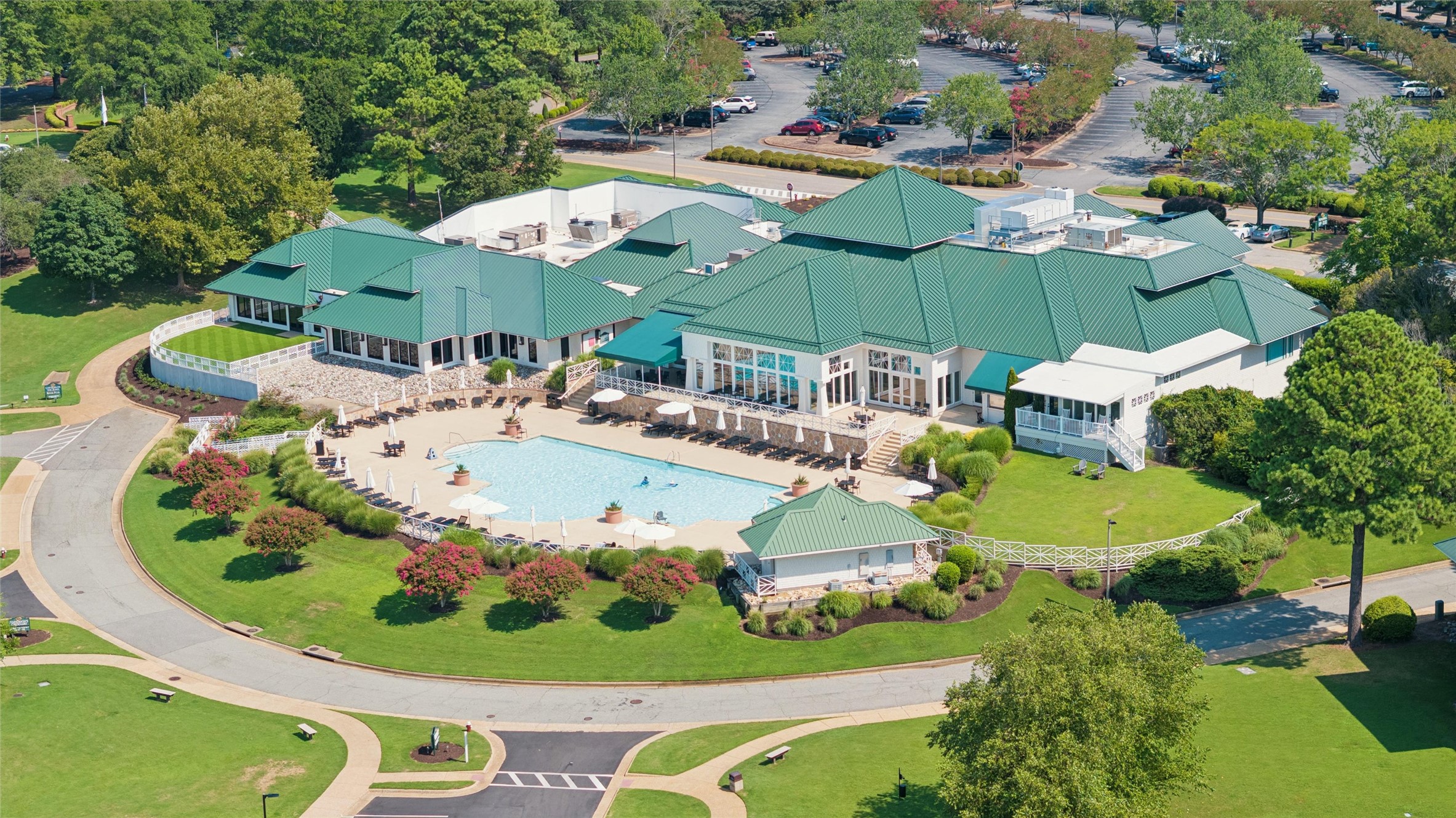 Aerial view of a clubhouse and swimming pool surrounded by landscaped lawns.