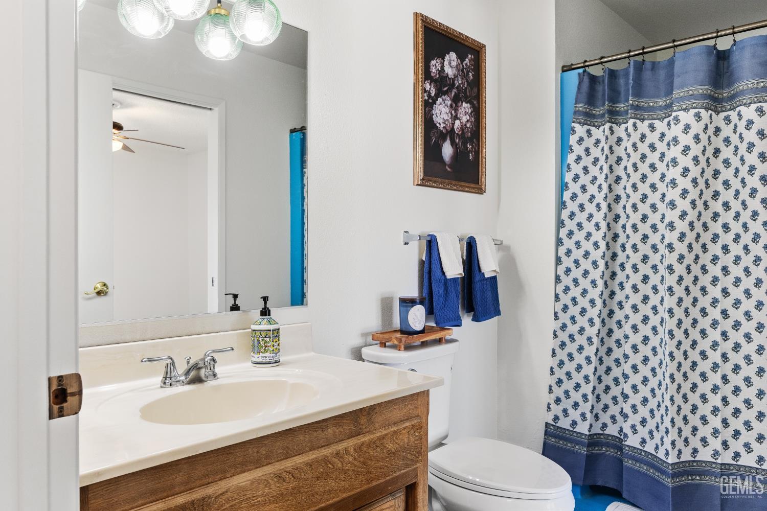 Bathroom with a wood vanity, white sink, and blue-and-white floral shower curtain.