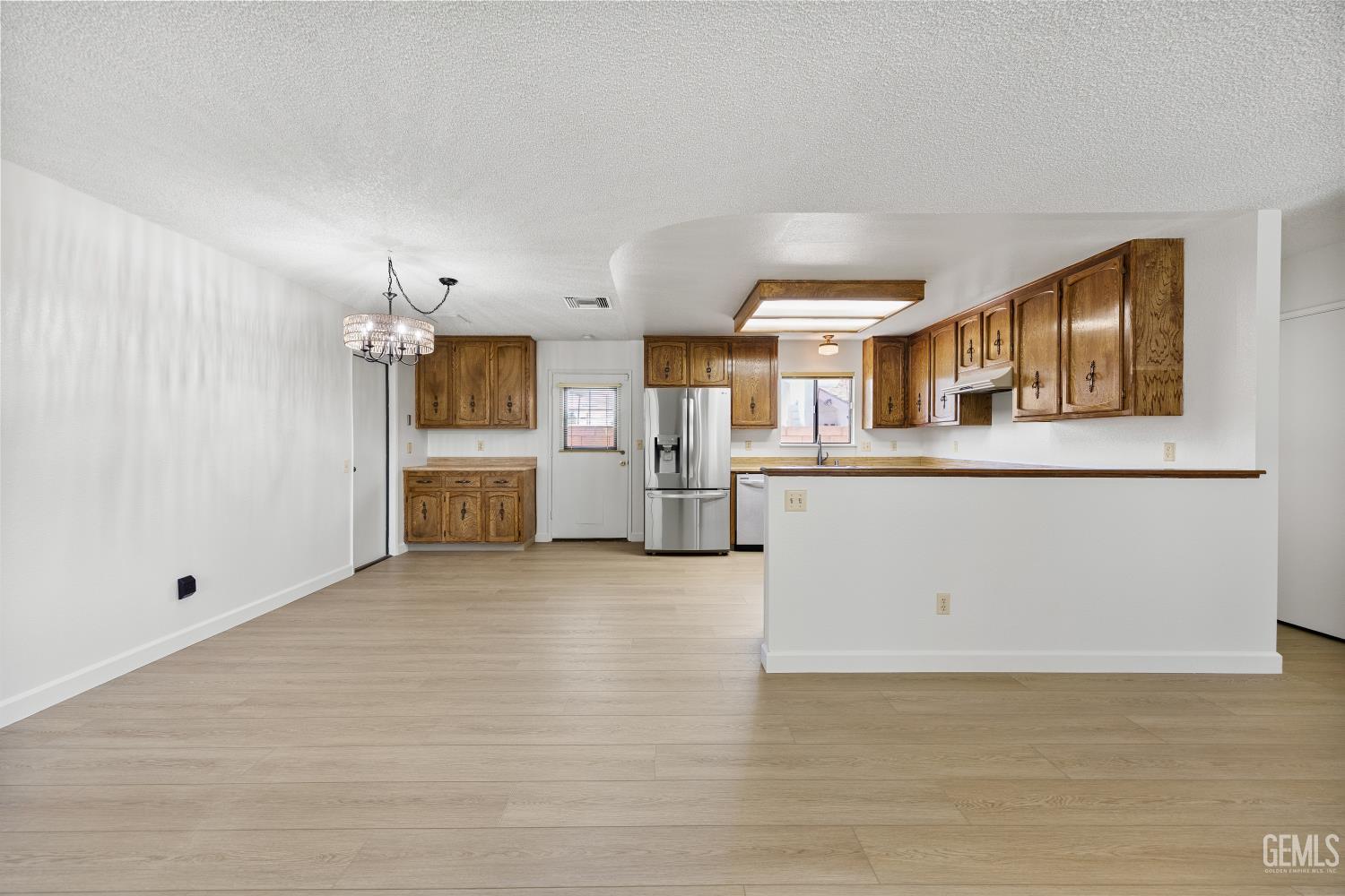 Unfurnished kitchen with oak cabinets, stainless steel appliances, and a peninsula counter.
