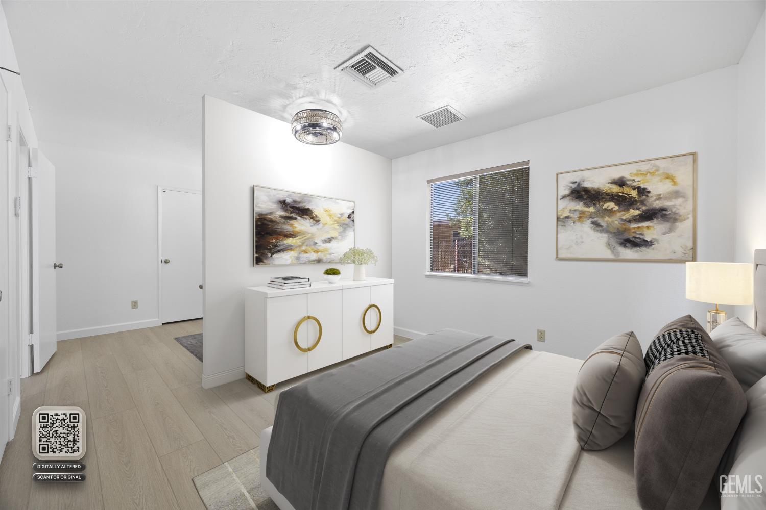 Bedroom with a white-and-gray bed, gold-handled cabinet, abstract art, and a window with blinds.