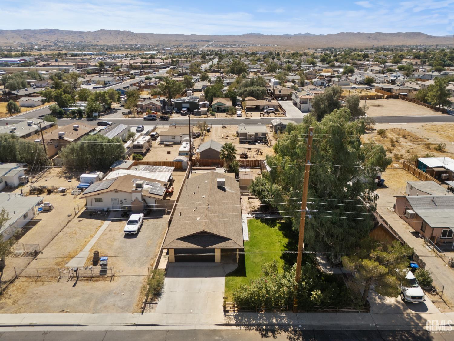 Aerial view of a home with a garage, broad driveway, and green lawn amid a Ridgecrest neighborhood.