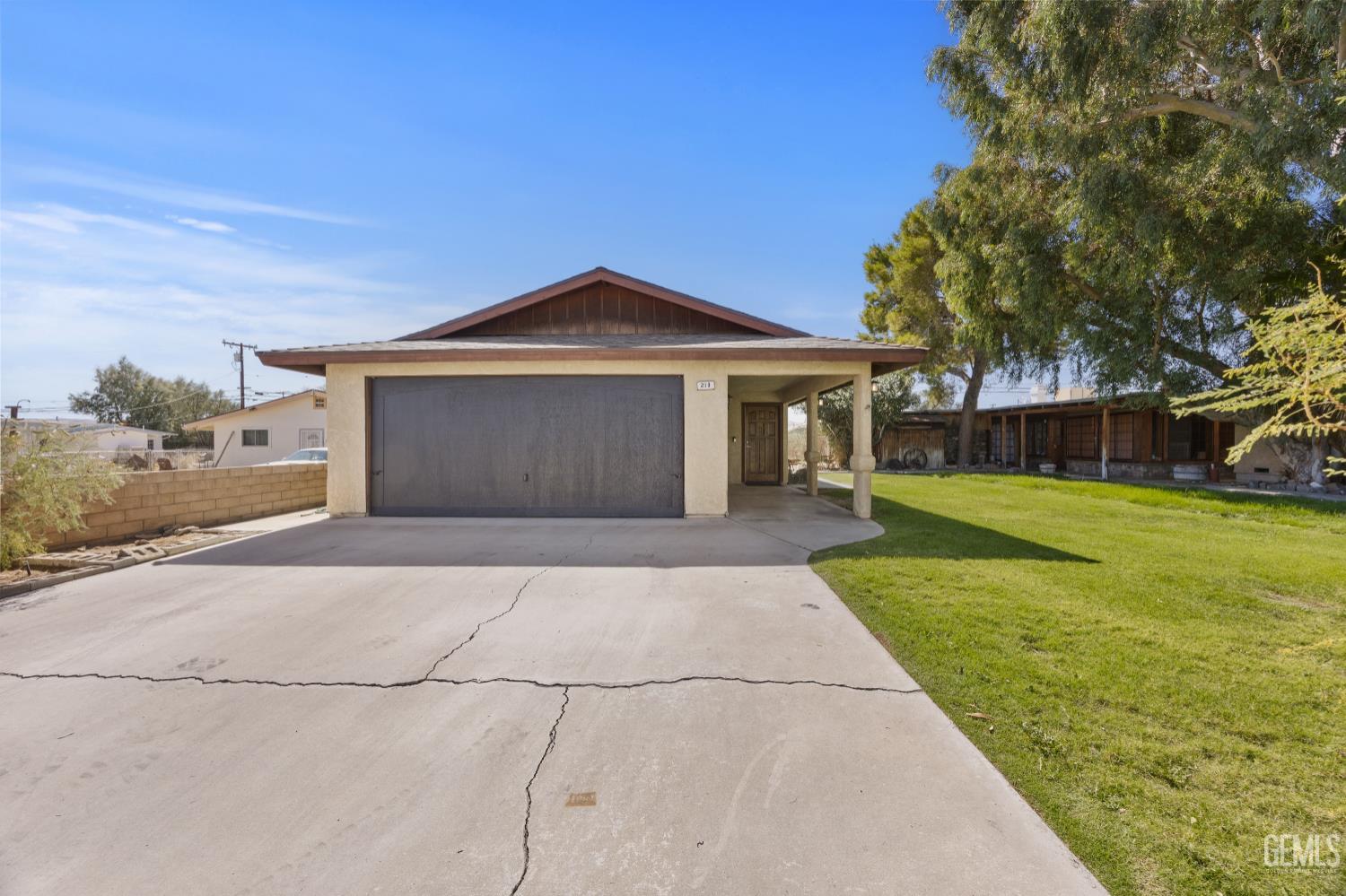 Single-story home with a double garage, covered entry, wide driveway, and lawn.