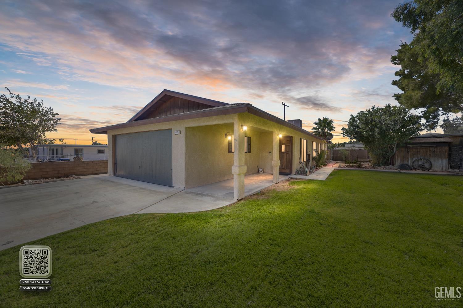 Single-story house with a gray garage, covered entry, driveway, and lawn at dusk.