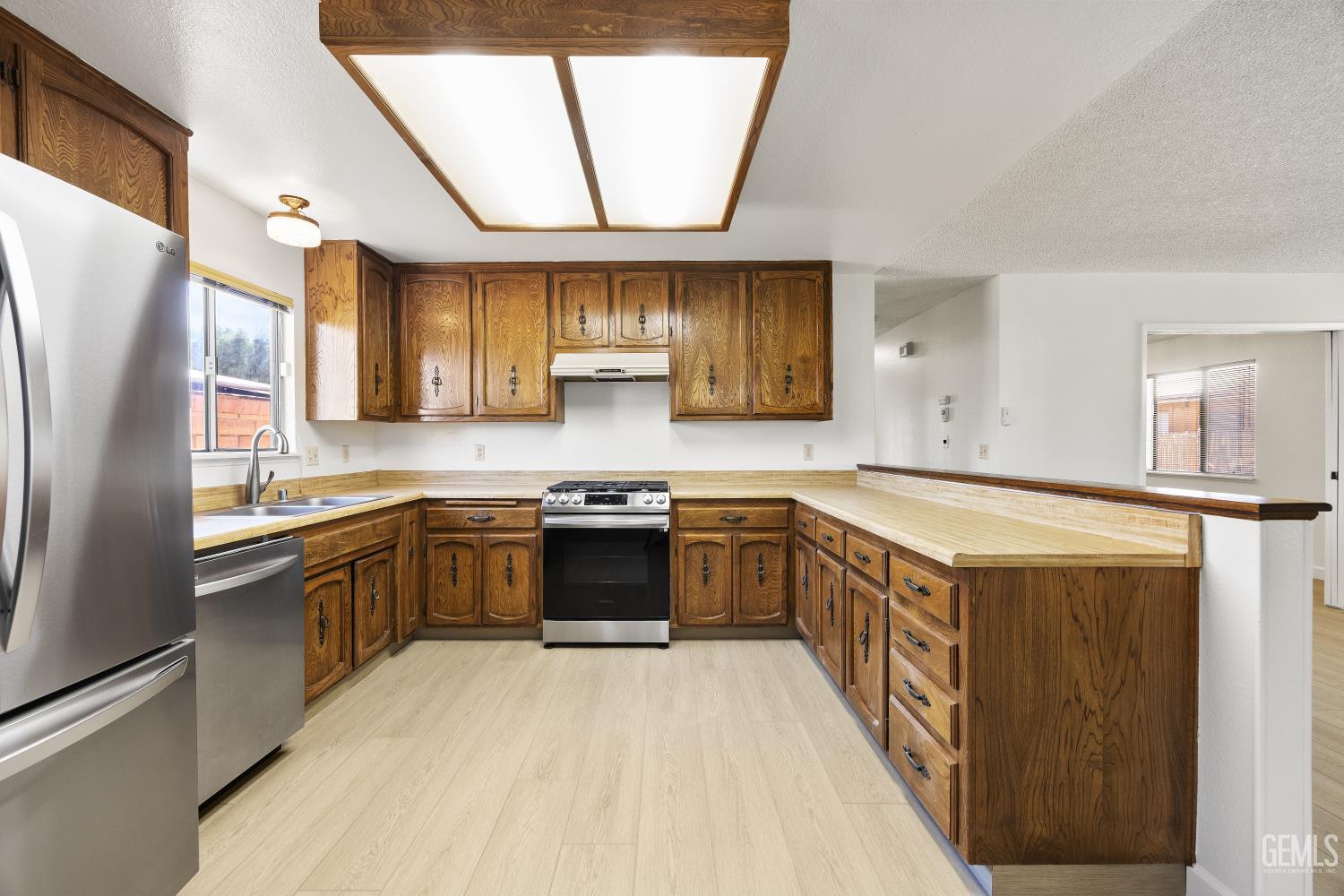 Kitchen with dark wood cabinetry, light counters, and stainless-steel appliances.