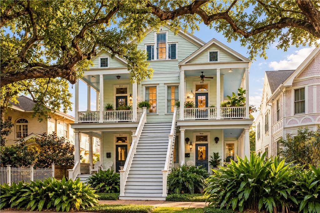 Pale green New Orleans home with broad front stairs, upper galleries, and a live oak canopy.