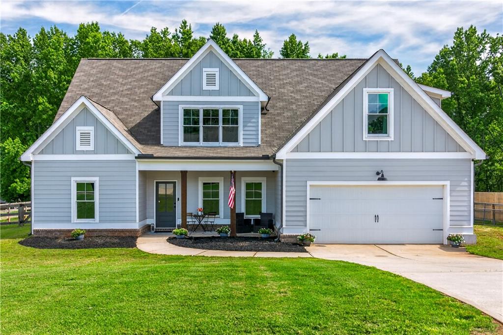 Light blue-gray two-story house with white trim, a covered entry, and an attached double garage.