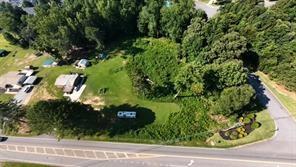 Aerial view of a wooded property with a grassy clearing and road frontage.