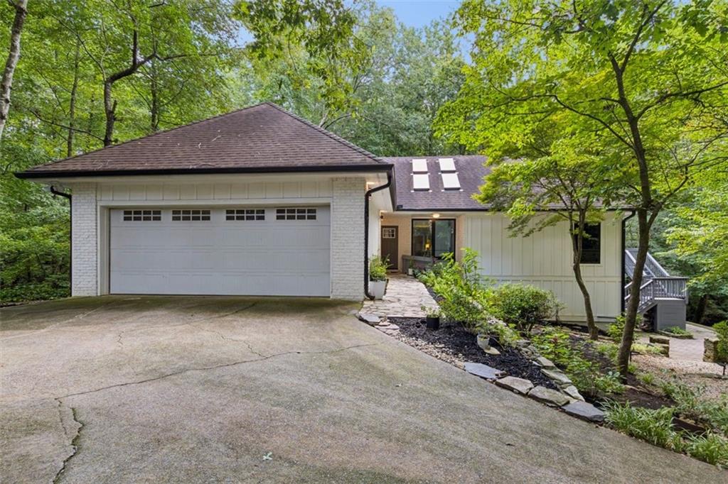 Home exterior with a large attached garage and driveway, surrounded by mature trees.