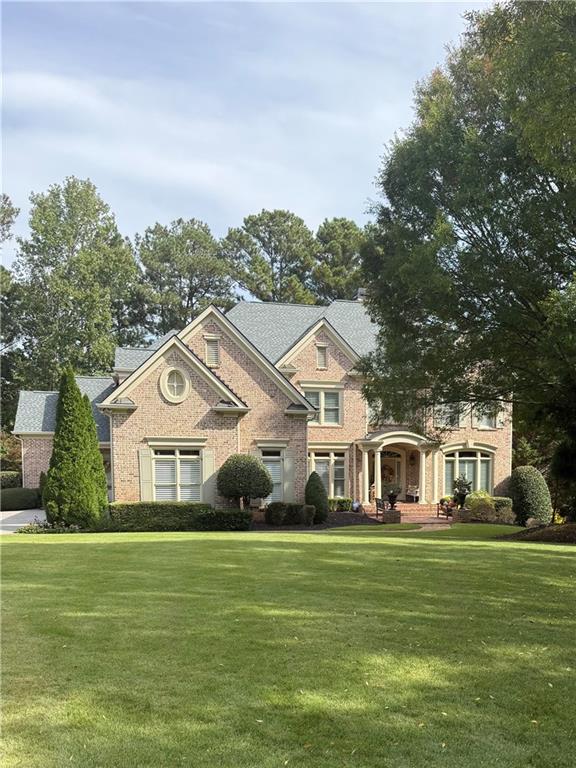 Two-story brick home with multiple gables, a covered entry, and a broad front lawn.