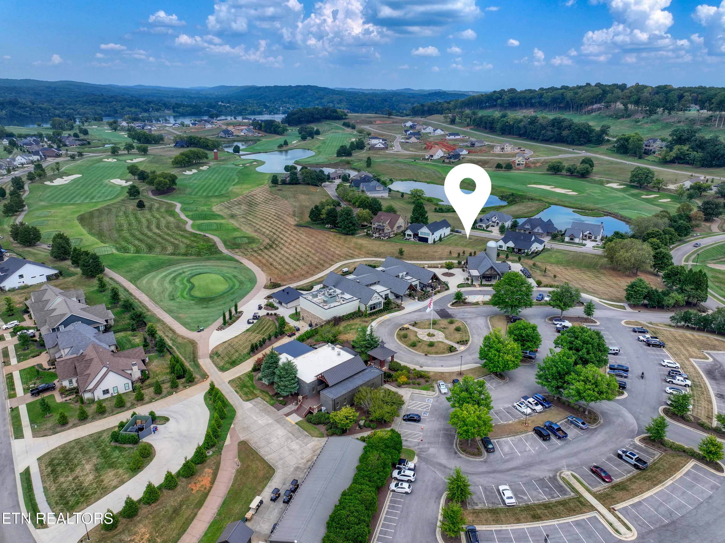 Aerial view of a golf-course community, with a map pin marking a home area beside ponds.