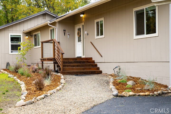 Single-story home with a gravel walkway, wooden entry steps, and landscaped beds.