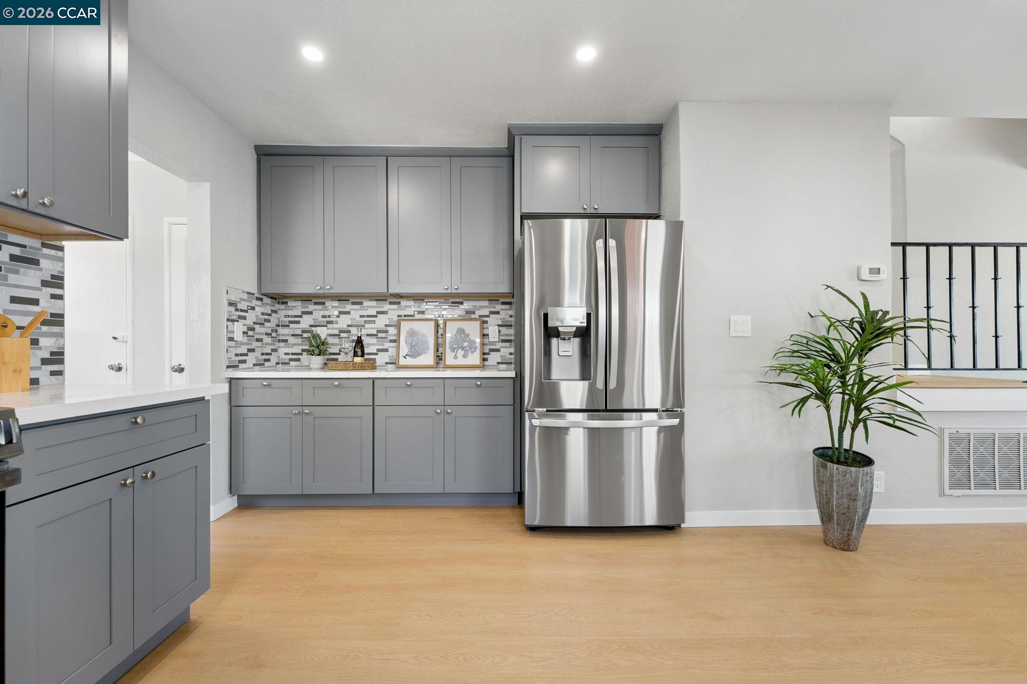 Kitchen with gray shaker cabinets, mosaic tile backsplash, and stainless steel French-door refrigerator.