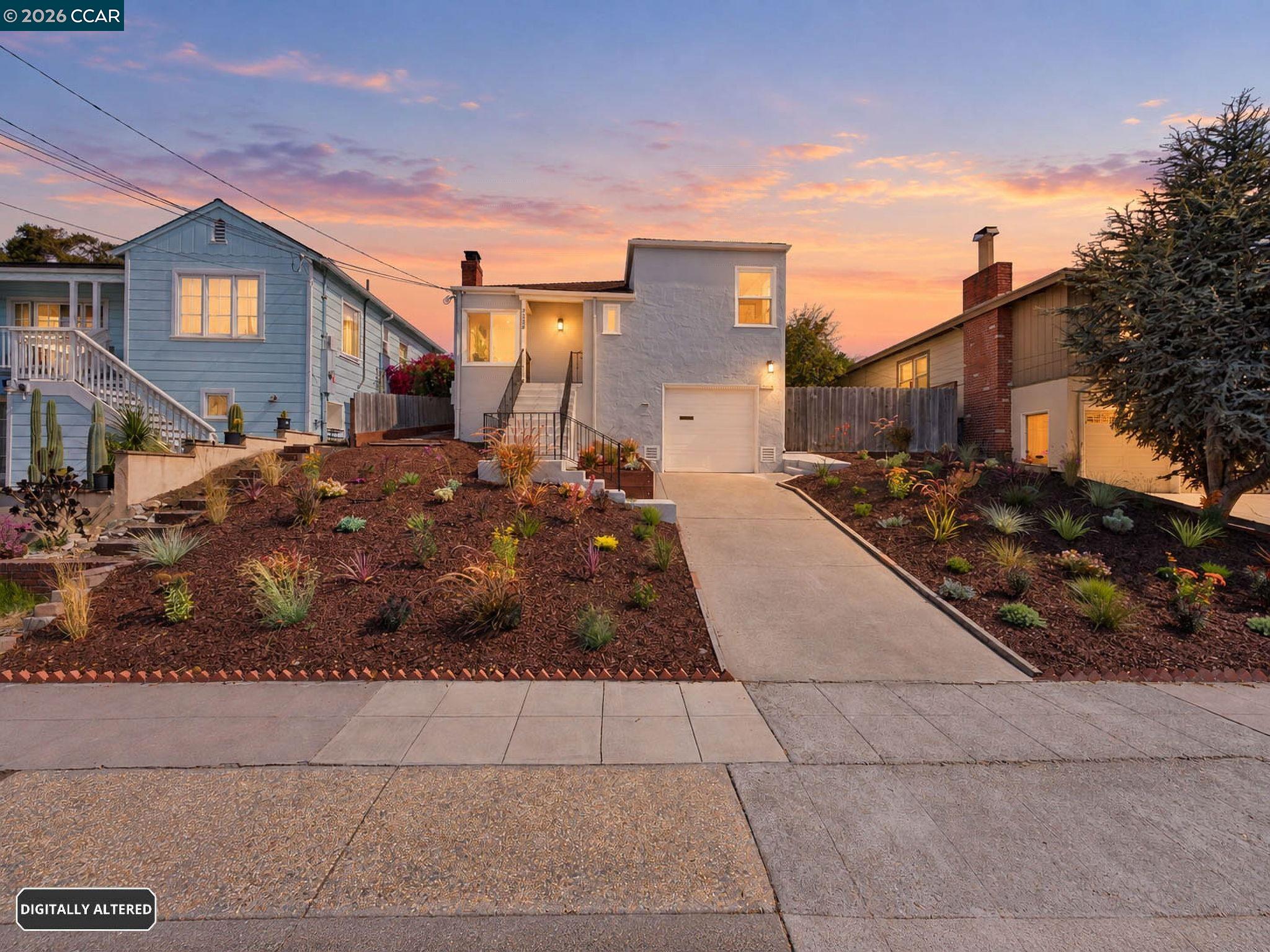 Light-gray home with a broad driveway and landscaped front yard at sunset.